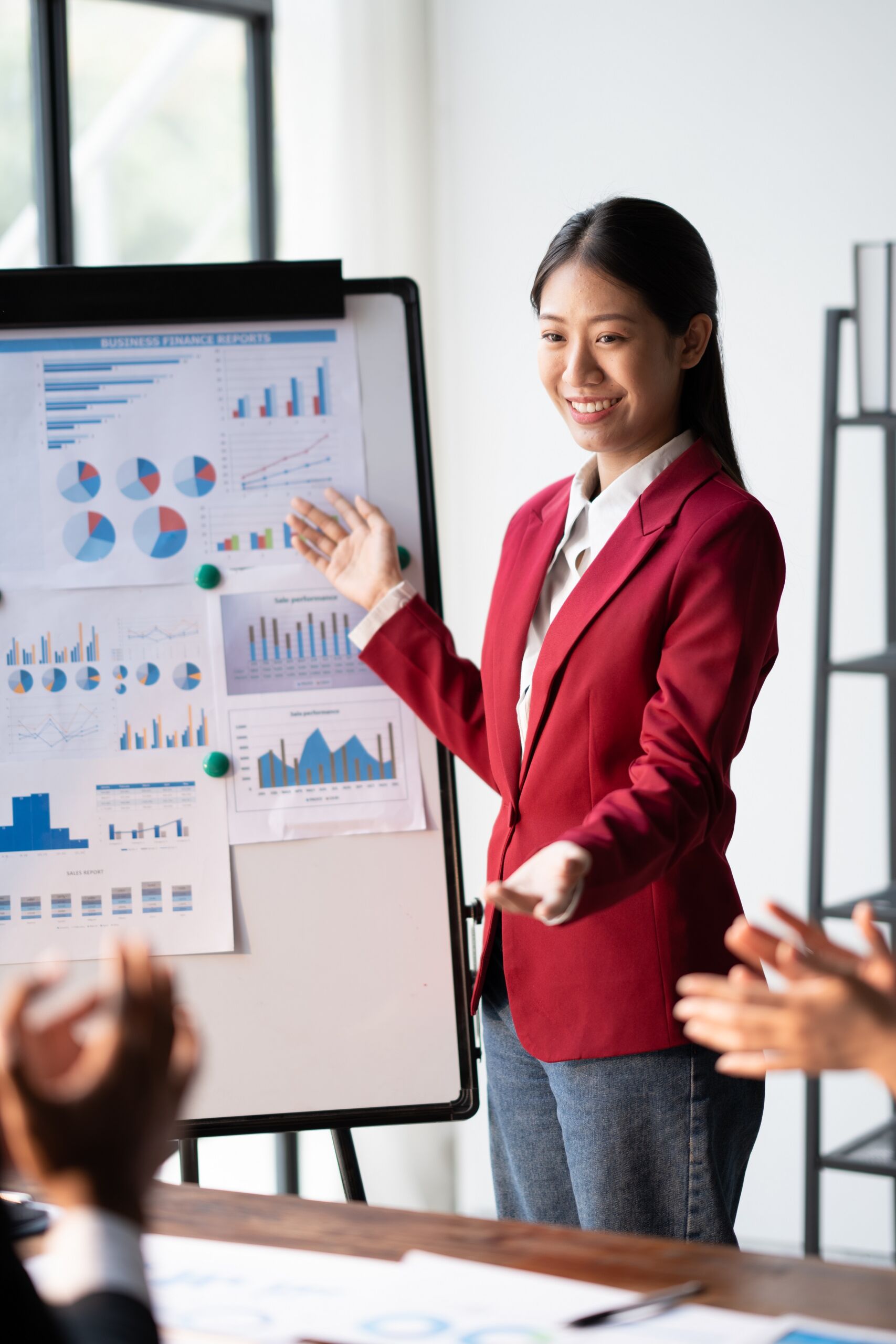 Equipo de trabajo aplaudiendo a mujer enseñando estadísticas en tablero digital.