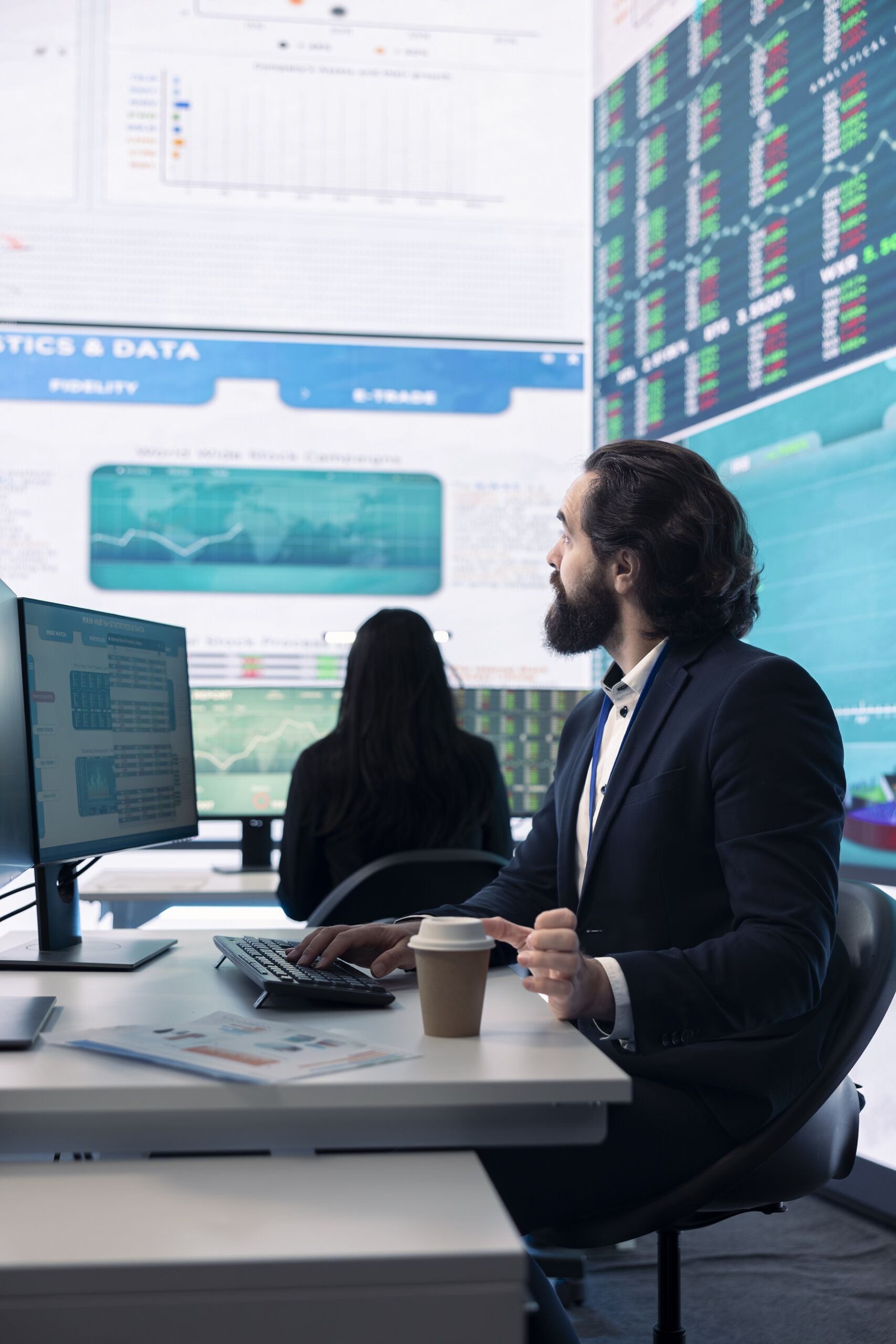 Hombre de negocios mirando panel de datos en oficina con compañera de fondo trabajando